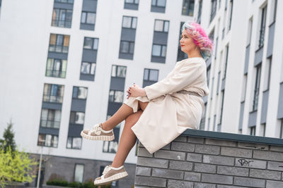 Smiling woman sitting with legs crossed while looking away