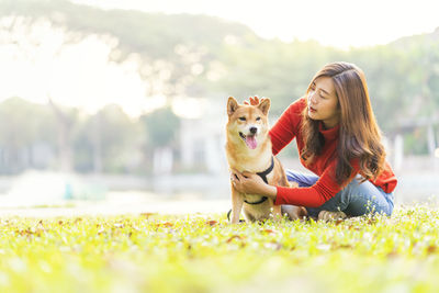 Pet lover concept. an asian woman is sitting with a shiba inu dog by the pool. the girl playing dog.