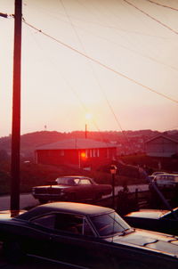 Cars on city against sky during sunset