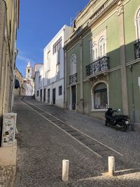 Road by buildings in city against sky