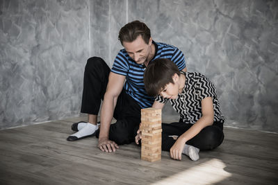 Father and son playing with wooden blocks on hardwood floor at home