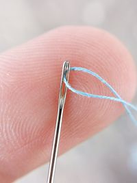 Close-up of needle and thread on human hand