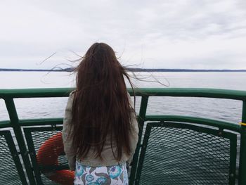 Rear view of woman with long hair traveling in boat over lake against sky