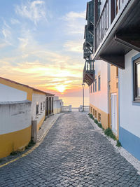 Footpath amidst buildings against sky during sunset