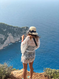 Rear view of woman standing on mountain over sea