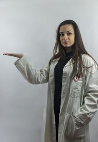 Portrait of young woman standing against white background