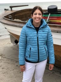Portrait of smiling woman standing by boat at beach