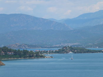 Scenic view of sea by mountains against sky