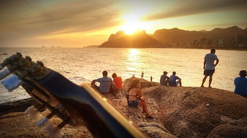 People on beach against sky during sunset