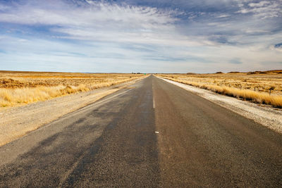 Road passing through land against sky