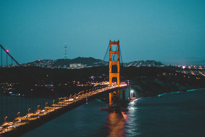 Illuminated bridge over sea against sky at night