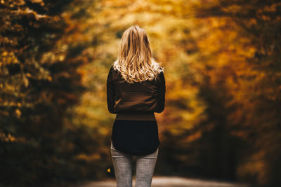 Rear view of woman with umbrella walking in autumn