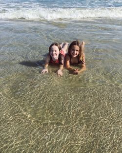 Portrait of smiling girls lying at beach