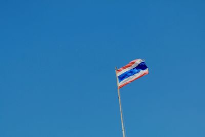 Low angle view of flag against clear blue sky