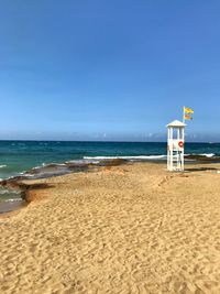 Lifeguard hut on beach against blue sky