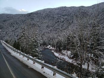 Empty road by mountains against sky during winter