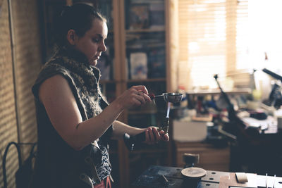 The master woman near the bench works with tools, on the torch boils water with a metal plate. 