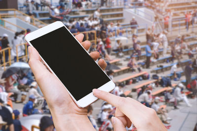 Midsection of woman holding mobile phone in city