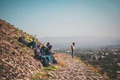 People looking at mountain against sky