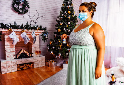 Midsection of woman with christmas tree at home