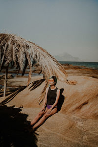 Full length o woman sitting on beach against sky