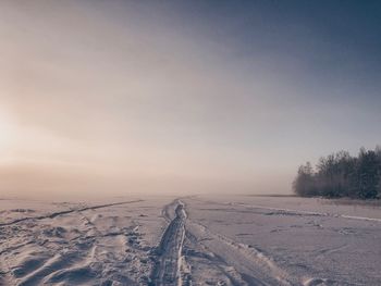 Snow covered land against sky during winter