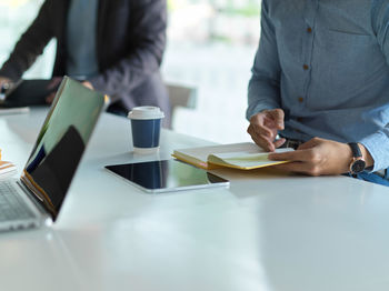 Rear view of man and woman using mobile phone on table