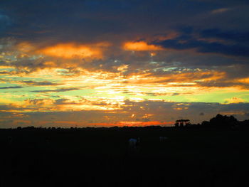 Scenic view of dramatic sky over silhouette landscape during sunset