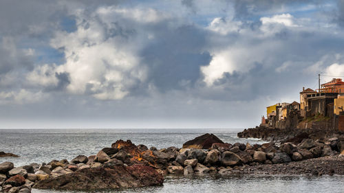 Panoramic view of village upon sea against sky