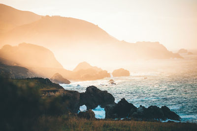 Scenic view of sea by rock formation during sunset