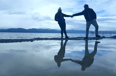 Silhouette couple standing by sea against sky