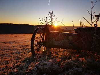 Bicycle on field against sky during sunset