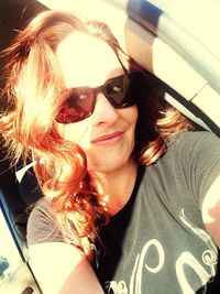 Portrait of smiling young woman wearing sunglasses against sky