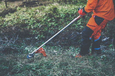 Man holding brushcutter cut grass and brush. lumberjack at work. gardener working outdoor in forest