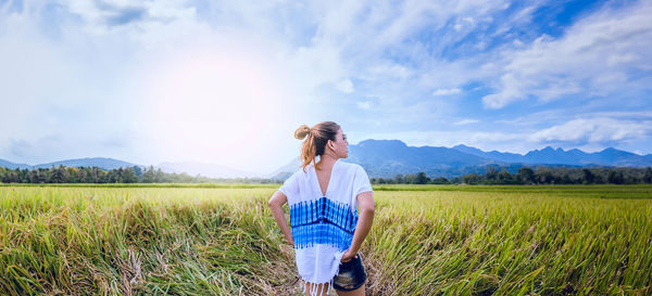 Rear view of woman standing on field against sky