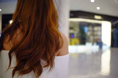Rear view of woman with long brown hair in shopping mall