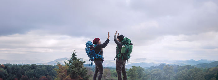 Rear view of woman standing on mountain against sky