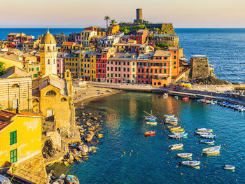 High angle view of illuminated buildings by sea against sky