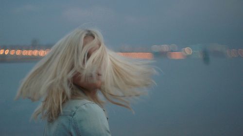 Young woman with tousled hair at dusk