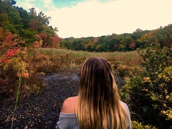 Rear view of woman against trees on landscape