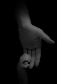 Close-up of father holding hands against black background