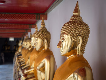 Row of golden buddha statues at wat pho temple, bangkok, thailand