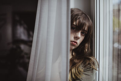 Portrait of woman by window curtain