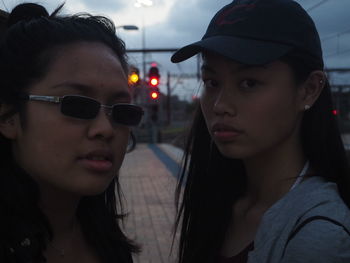 Portrait of friends standing on railroad station platform at dusk