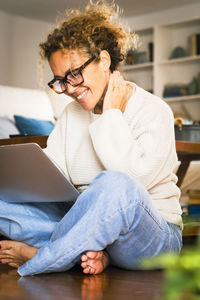 Young woman using laptop while sitting on sofa at home