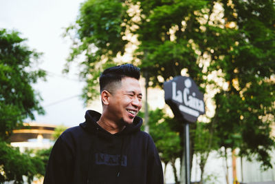 Portrait of a smiling young man standing against plants