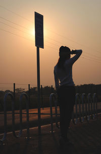 Man standing on street against sky during sunset