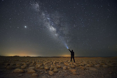 Rear view of man standing against sky at night