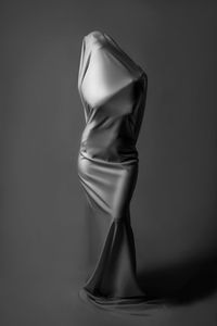 Mannequin wrapped in textile against gray background