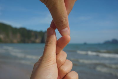 Cropped couple joining fingers at beach